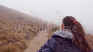 在潮湿多雾<strong>的</strong>天气里，穿着雨衣和背包在山上<strong>行走的</strong>徒步旅行妇女。 小女孩在山径上